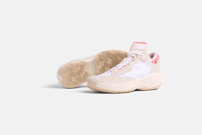 Side view of tan and pink New Balance basketball shoes.